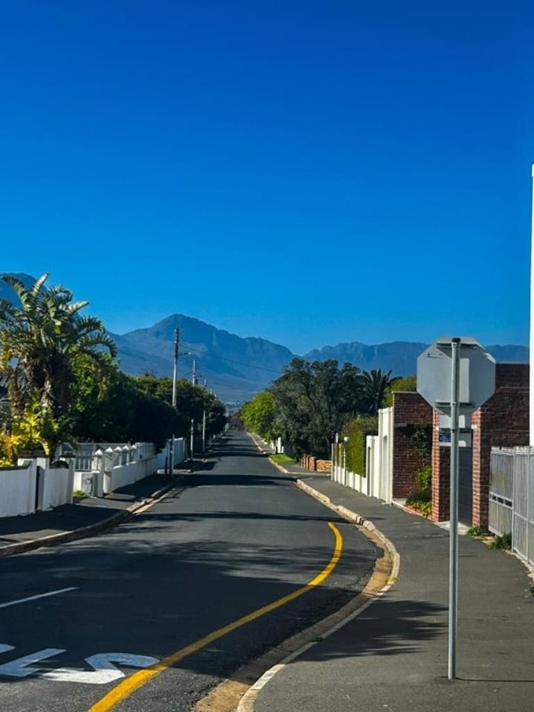 Residential street with STOP marking and mountain view under blue sky in Cape Town, South Africa