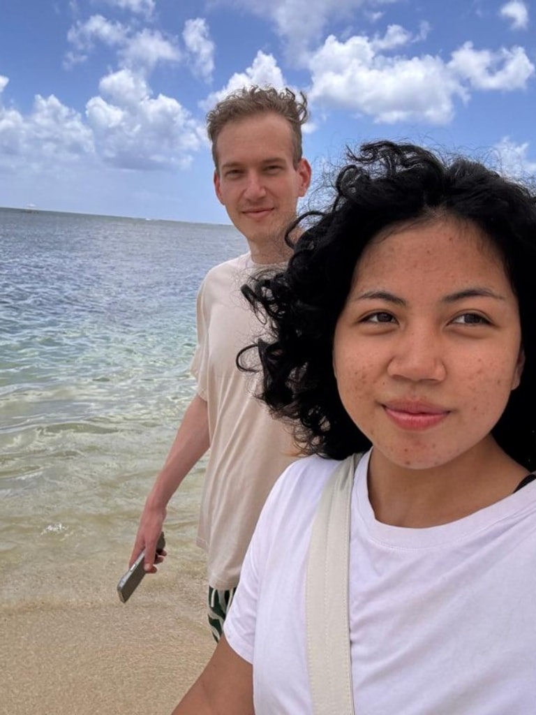 Couple on the beach with turquoise water and cloudy sky at Mon Choisy Public Beach, Mauritius